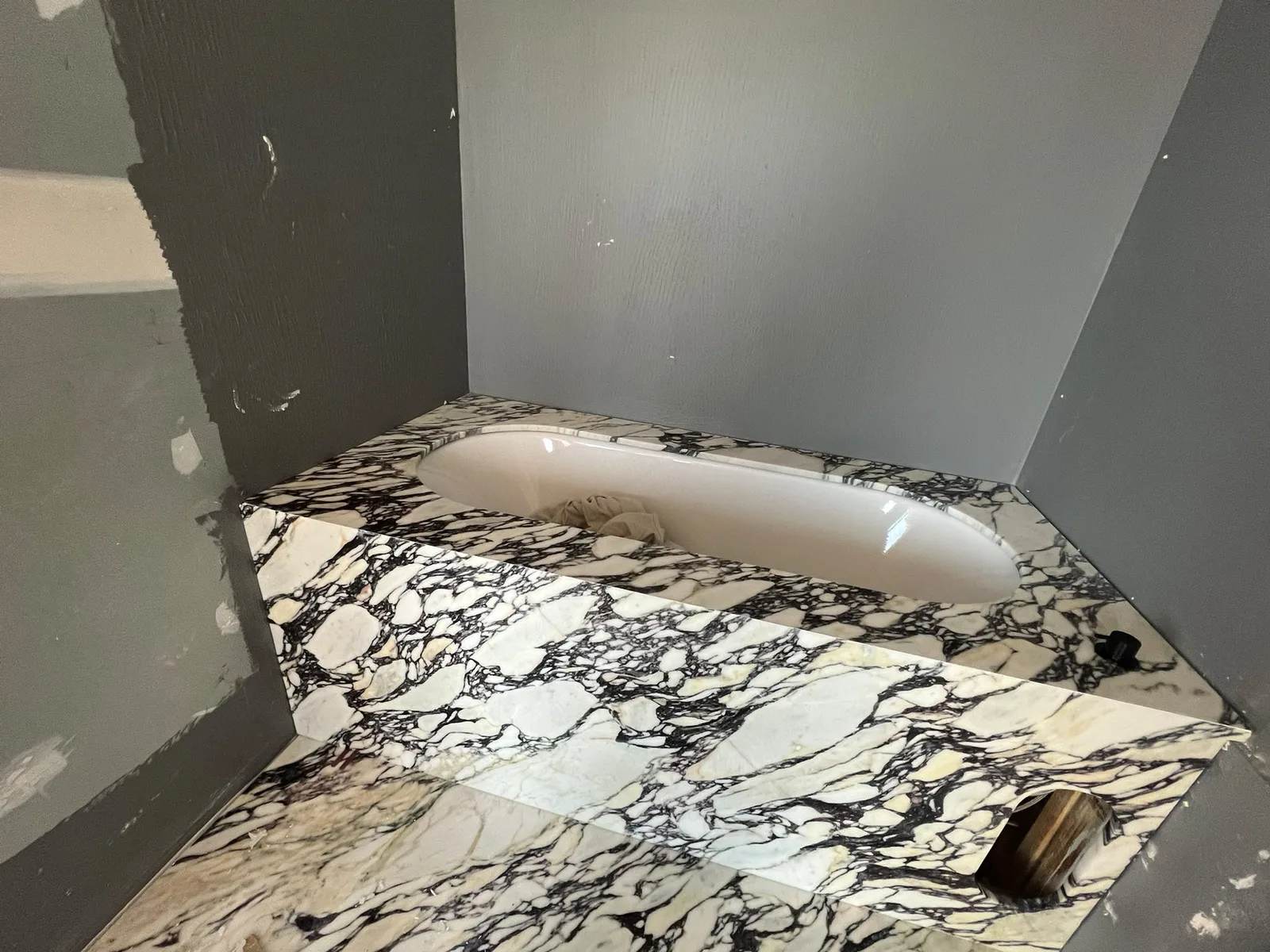 Luxury bathtub hob and shower surround with waterproof joints and clean marble cladding